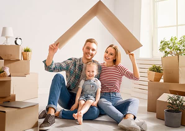 happy family of three in their new home with boxes surrounding