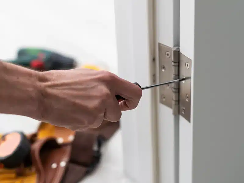 person putting on door hinge